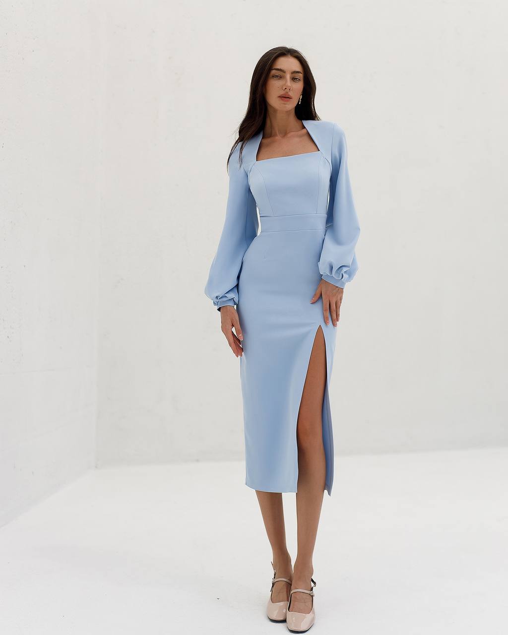 Woman wearing a light blue dress with a matching jacket against a white background