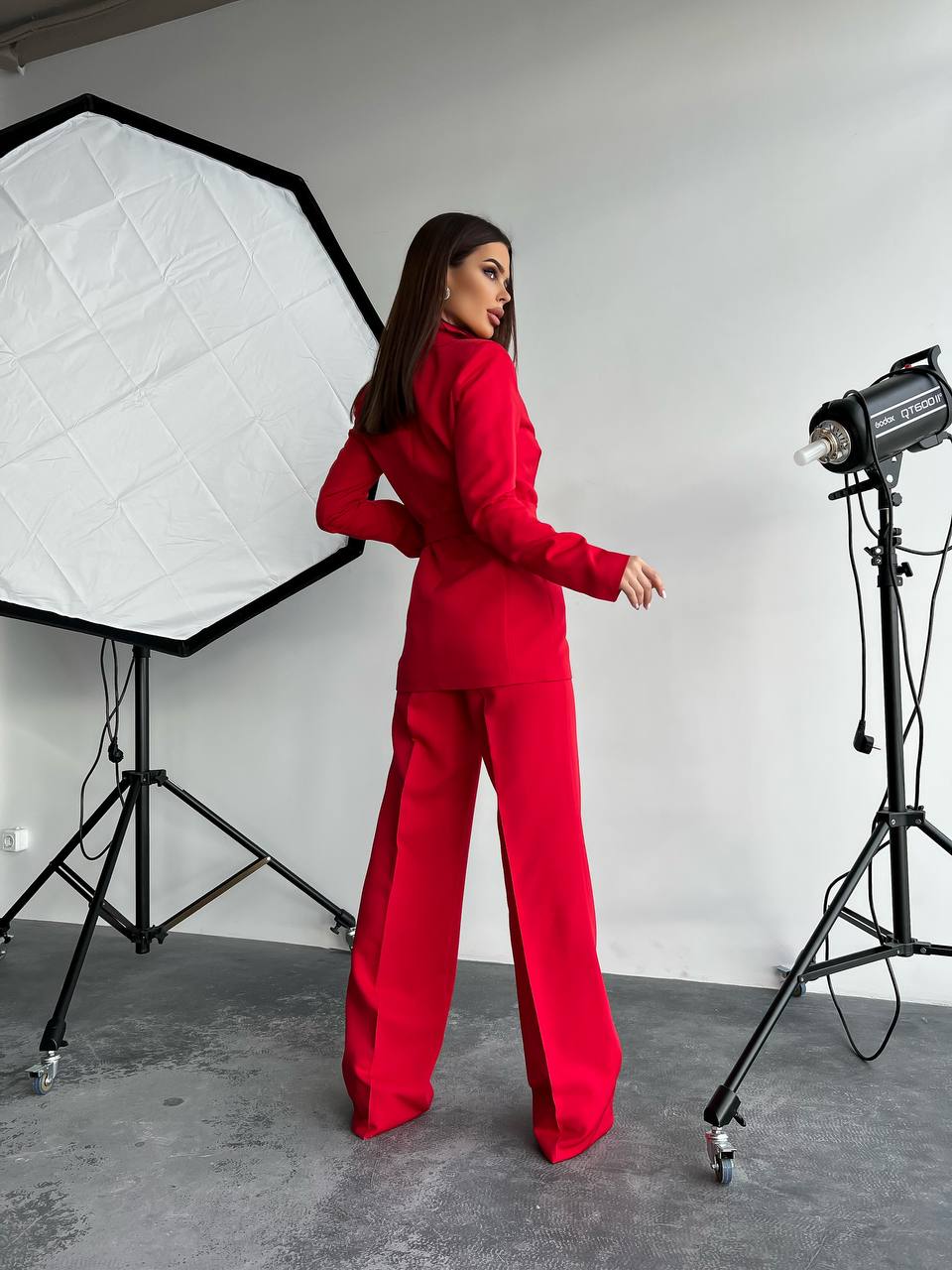 Person in a red outfit standing in a photo studio with lighting equipment.