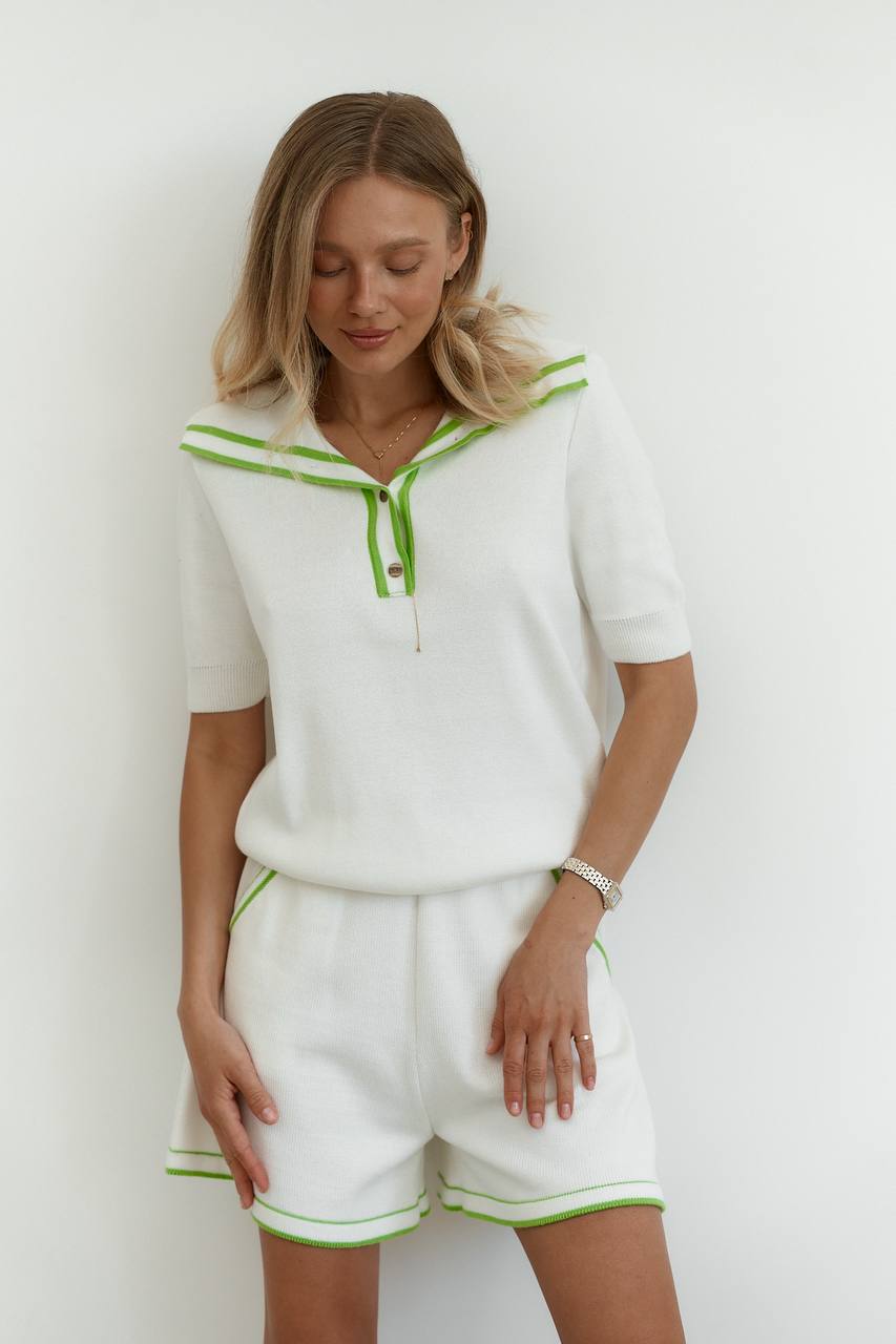 Woman wearing a white outfit with green accents against a white background