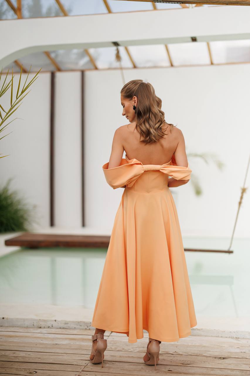 Woman in a peach dress standing by a poolside