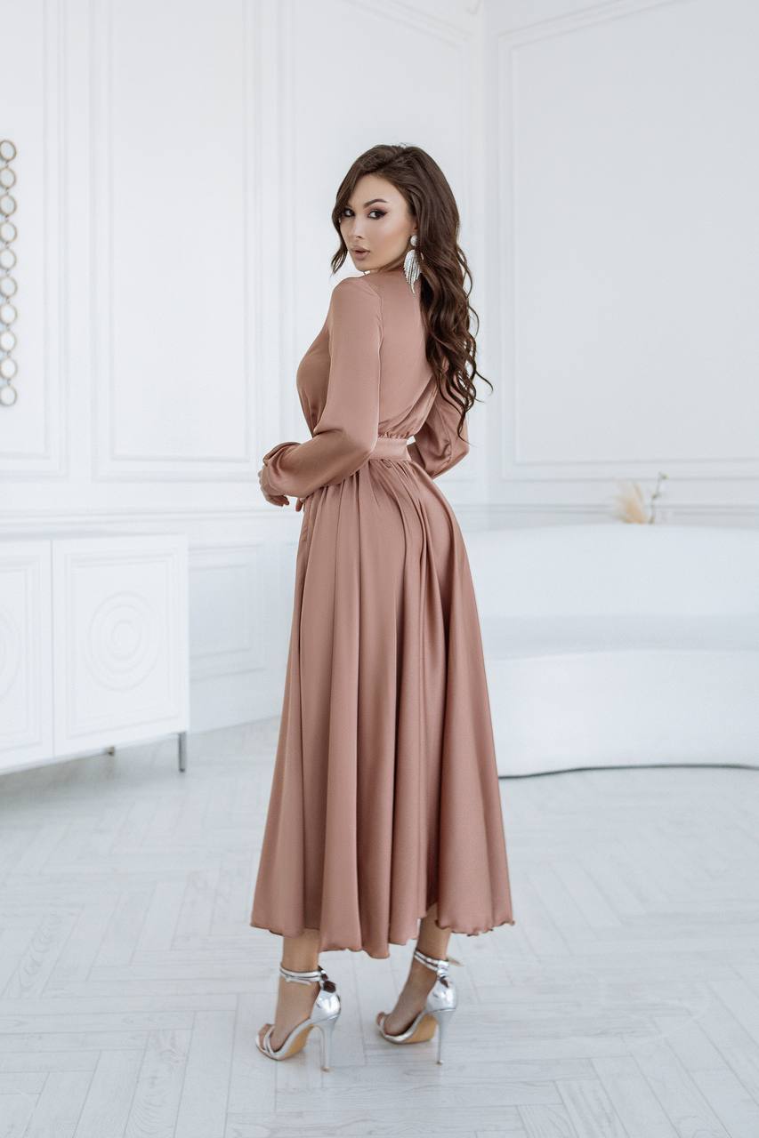 Woman wearing a long, light brown dress in a minimalistic setting