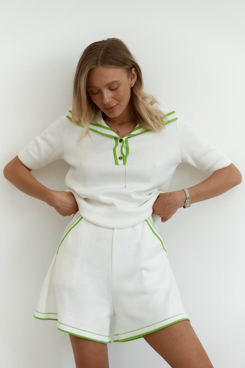 Woman wearing a white outfit with green accents against a white background