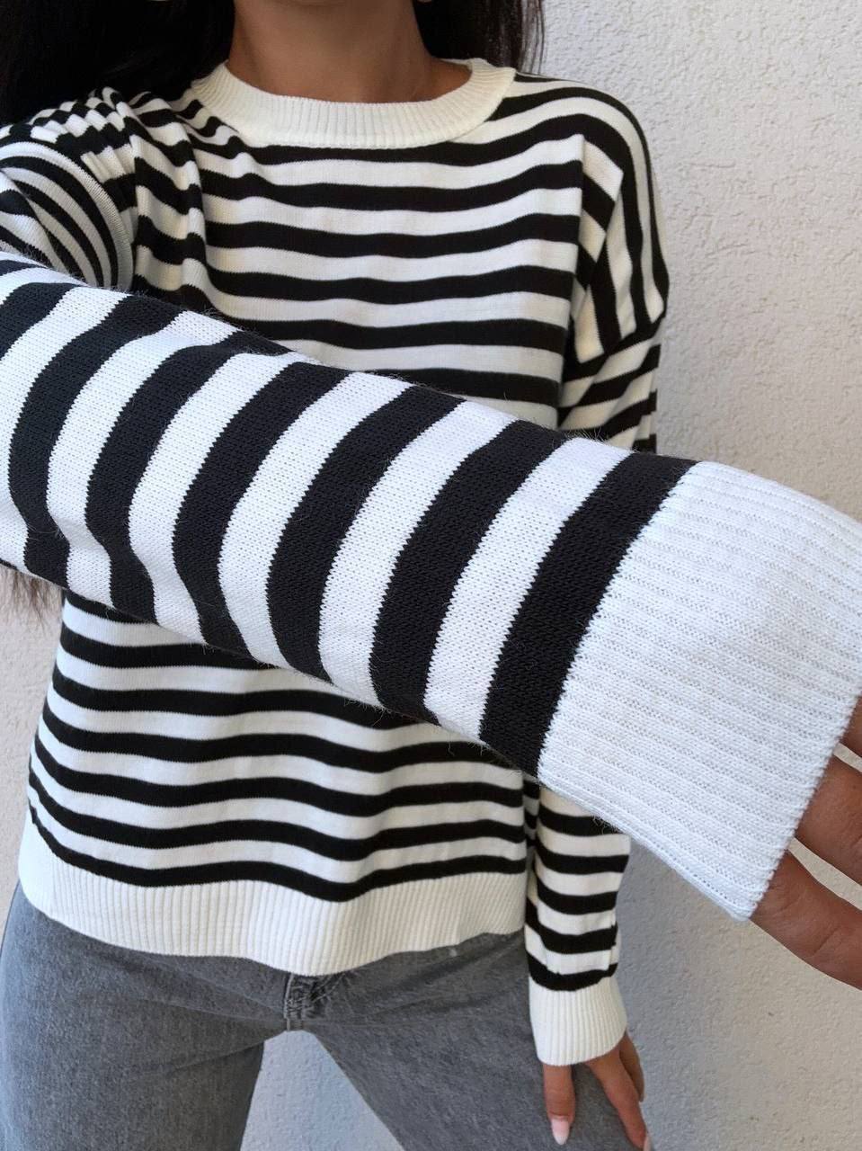 Person wearing a black and white striped sweater with a plain background