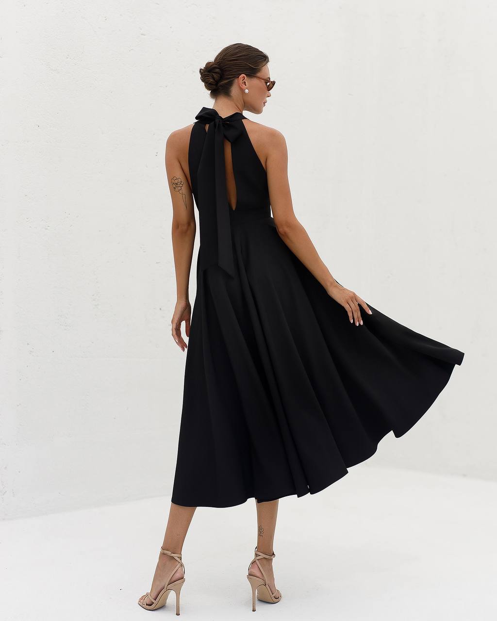 Woman wearing a black dress with a bow detail on a white background