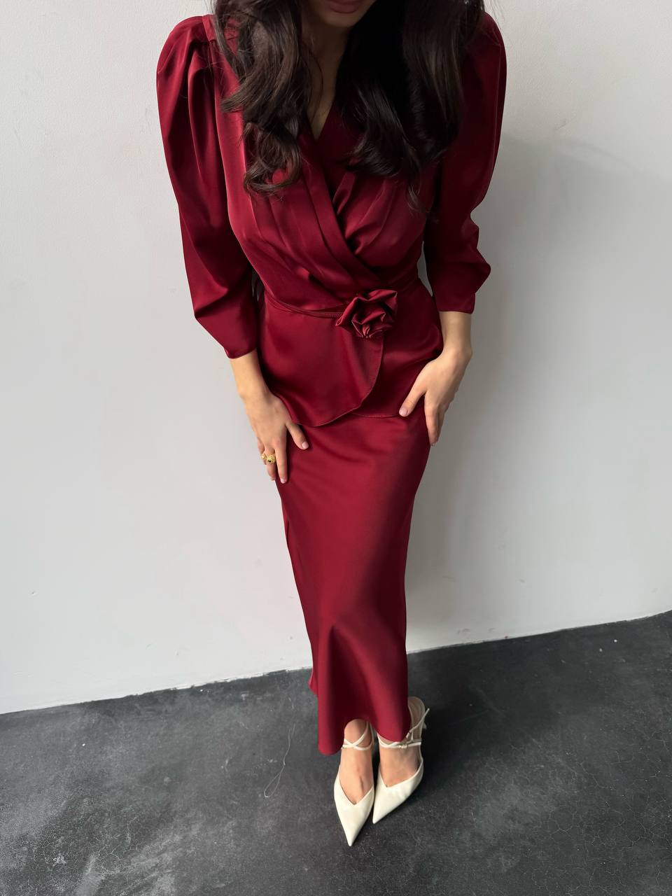 Woman wearing a red dress with puff sleeves against a plain background