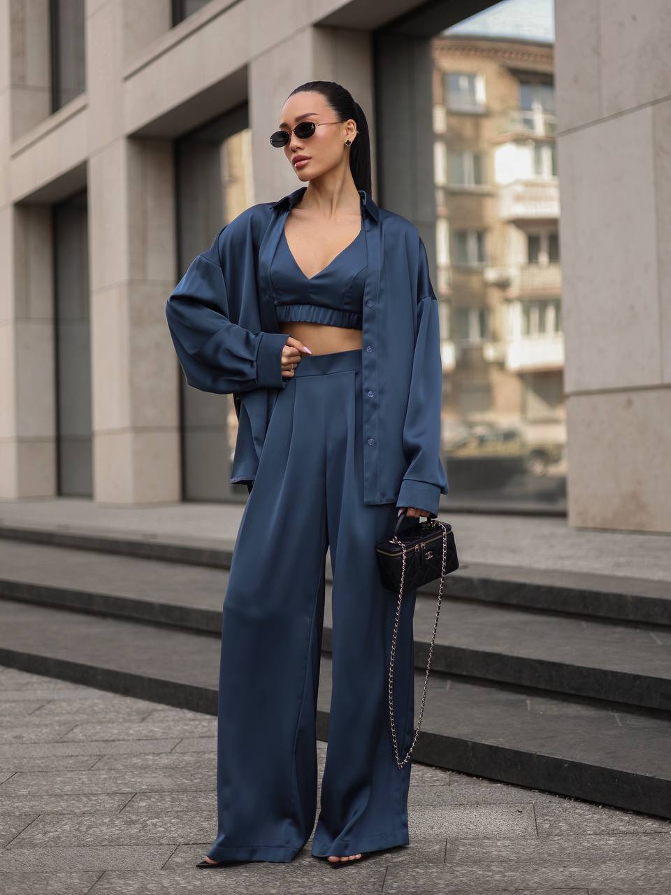 Woman in a blue outfit standing on a city street.