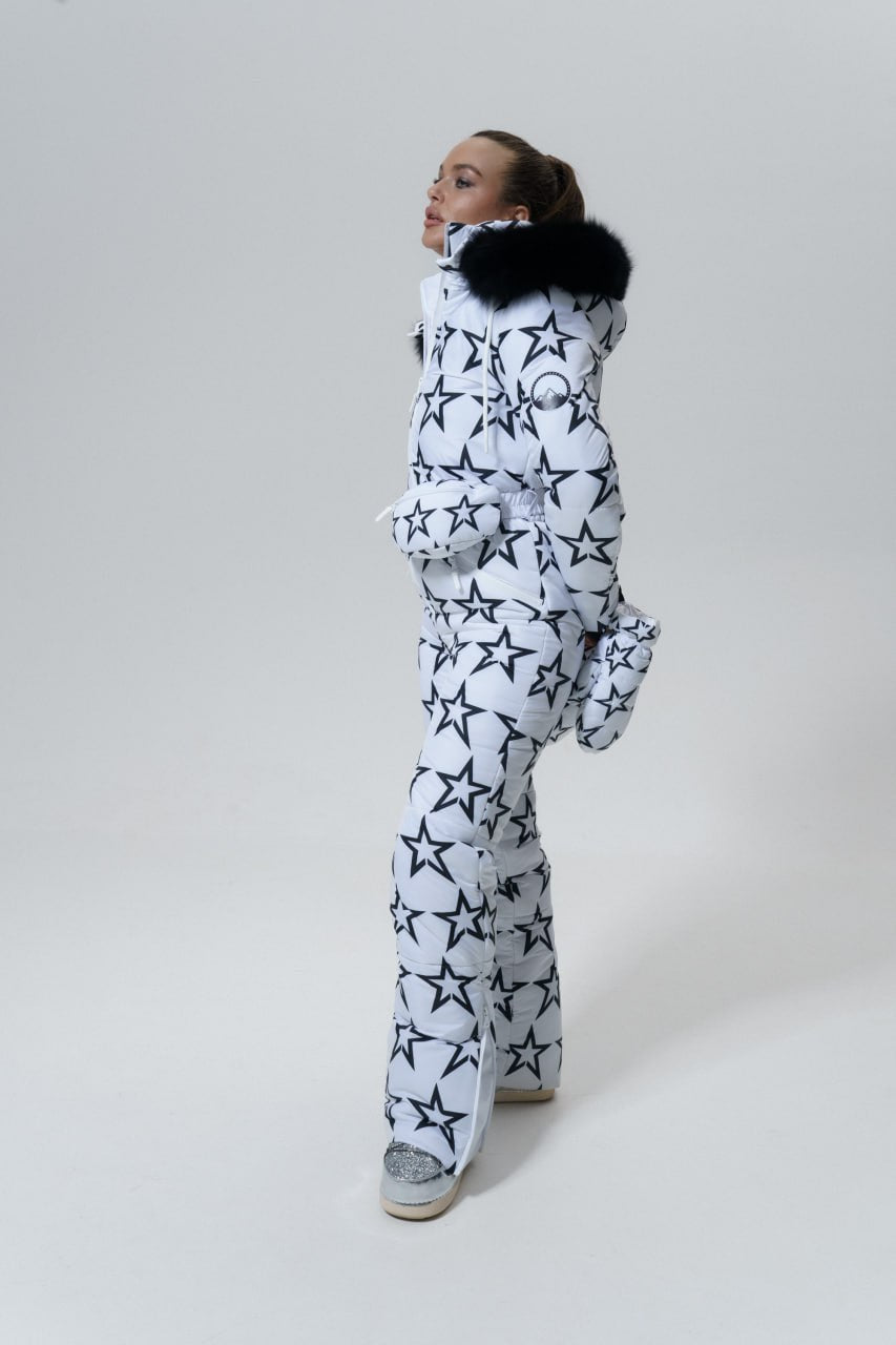Person wearing a white snowsuit with star patterns on a plain background