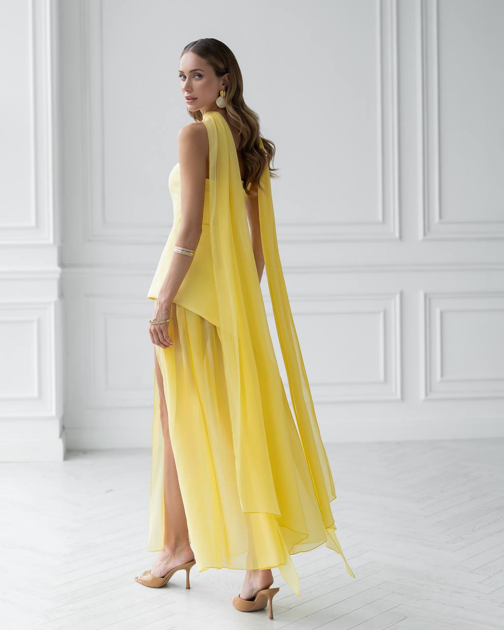 Woman wearing a yellow dress with a slit in a white room