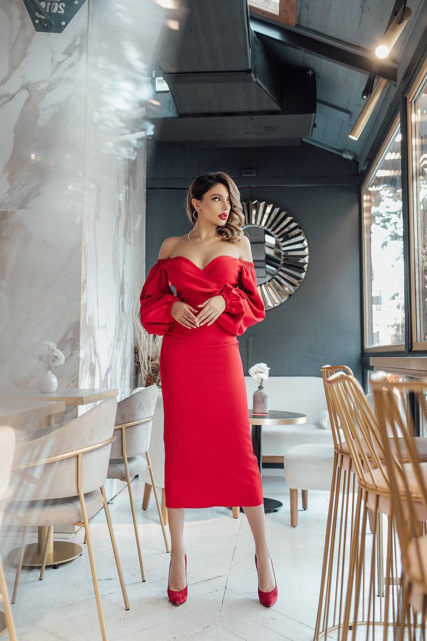 Woman in a red dress standing in a modern restaurant interior.
