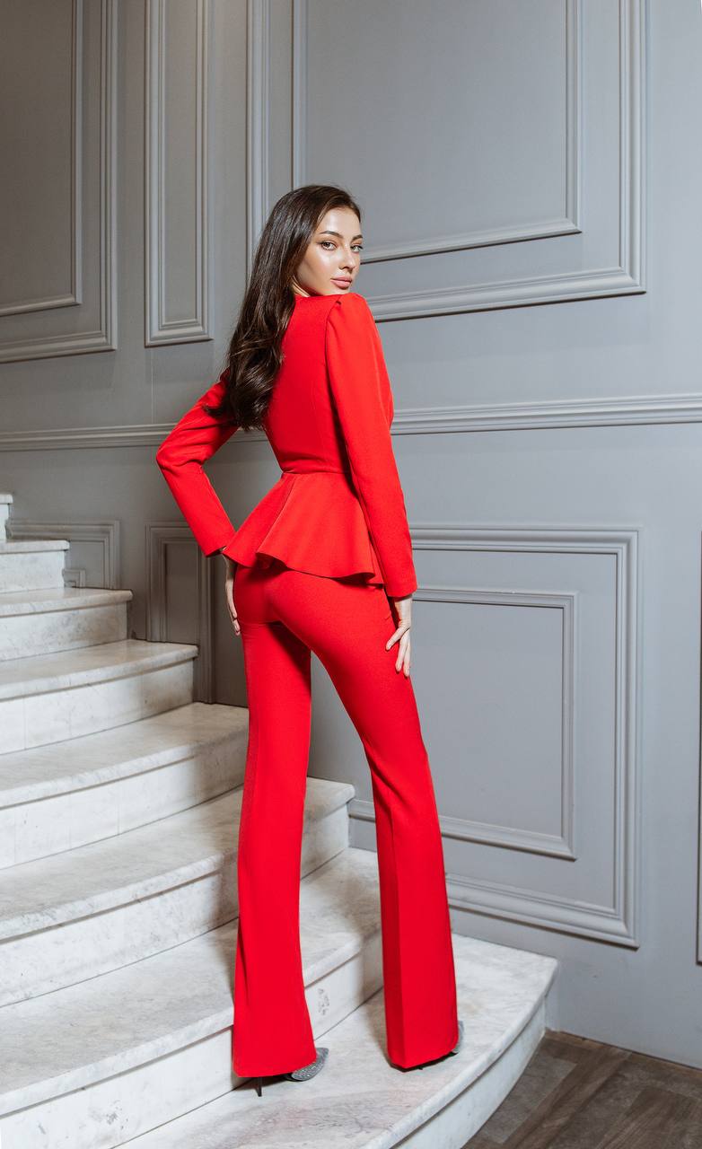 Woman in a red outfit standing on a staircase with gray walls.