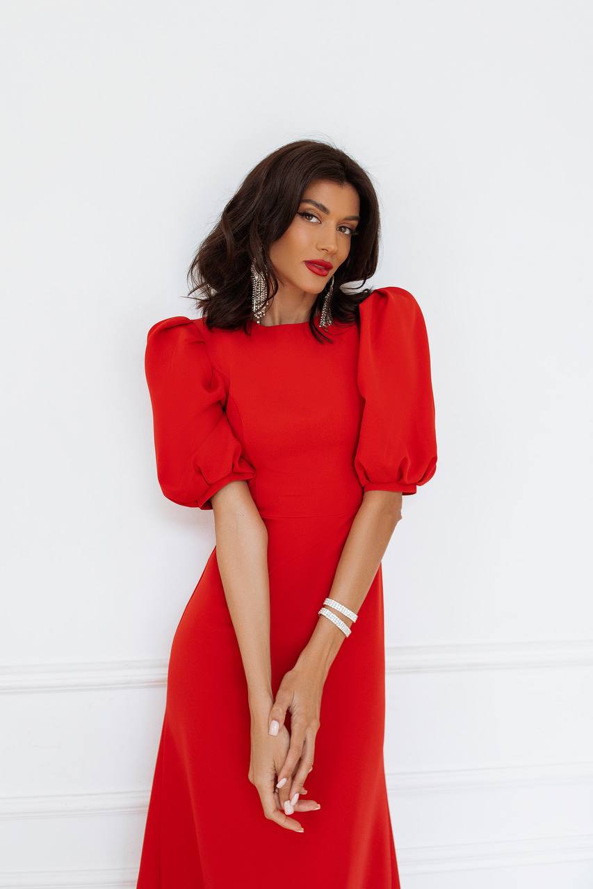 Woman wearing a red dress with puff sleeves against a white background