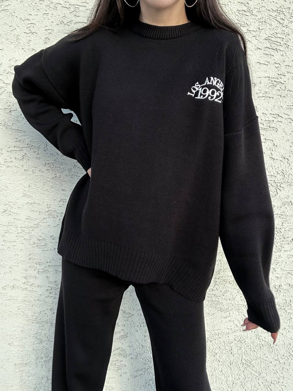 Person wearing a black sweater with text against a light gray background