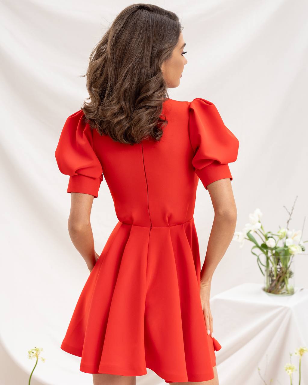 Woman wearing a red dress with puff sleeves against a white background