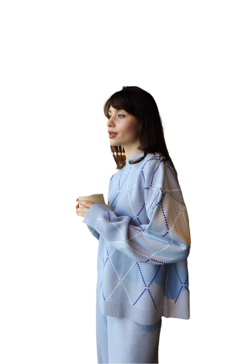 Woman wearing a light blue patterned sweater holding a cup against a white background