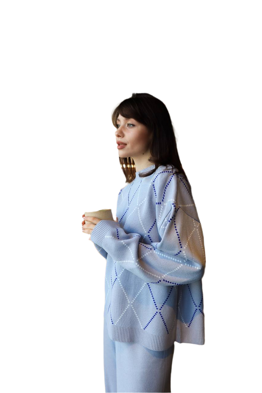 Woman wearing a light blue patterned sweater holding a cup against a white background