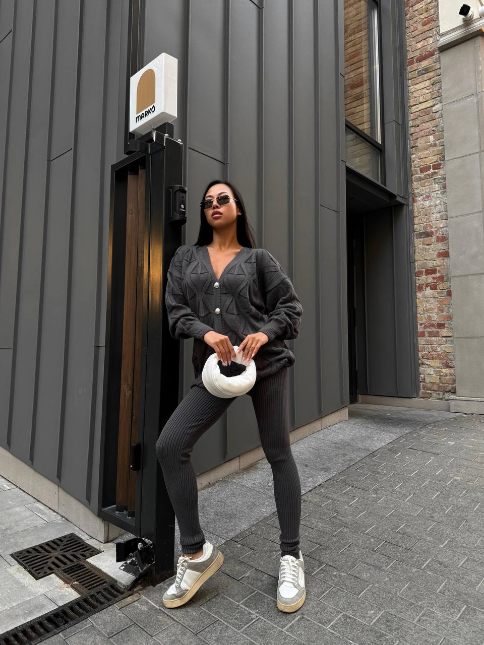 Woman in black outfit standing in front of a modern building entrance.