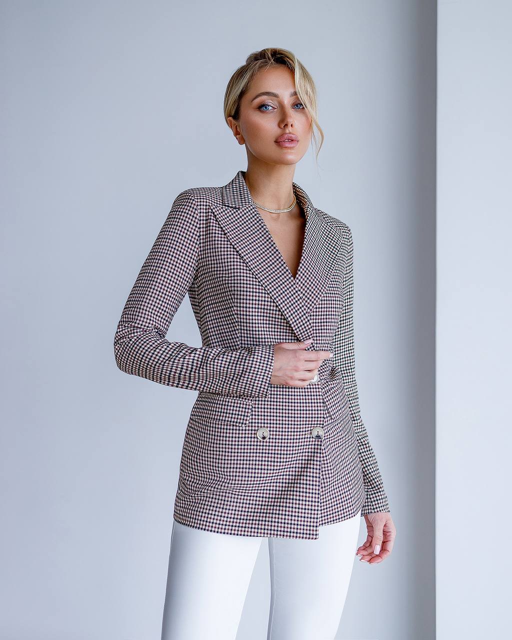 Woman wearing a checkered blazer against a plain background