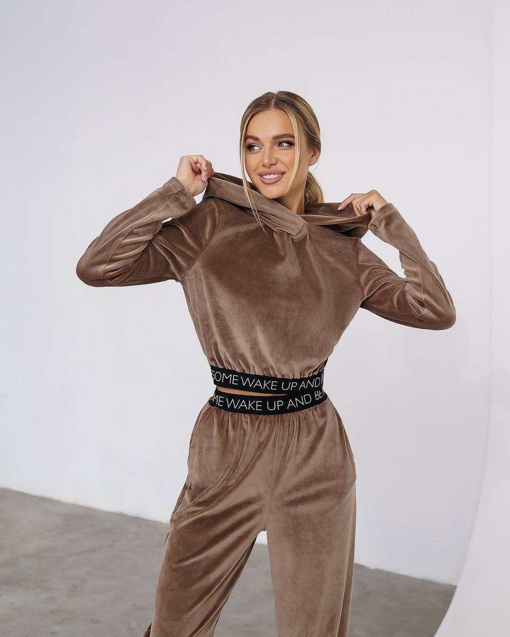 Woman wearing a brown velvet tracksuit with a white background