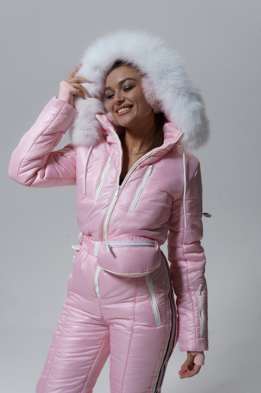 Person wearing a pink puffer suit with a fur-lined hood against a gray background