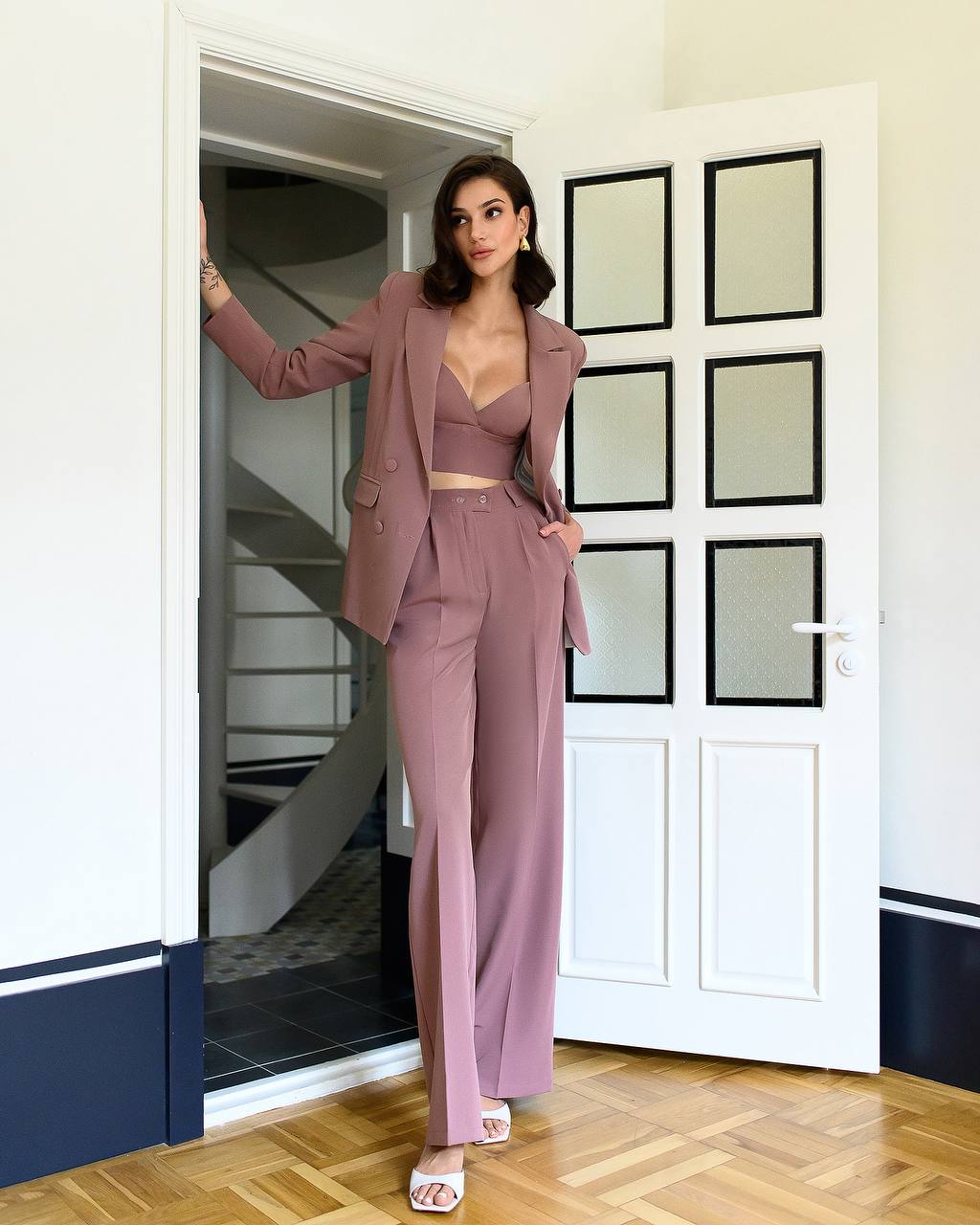 Woman in a mauve suit standing in a modern interior setting