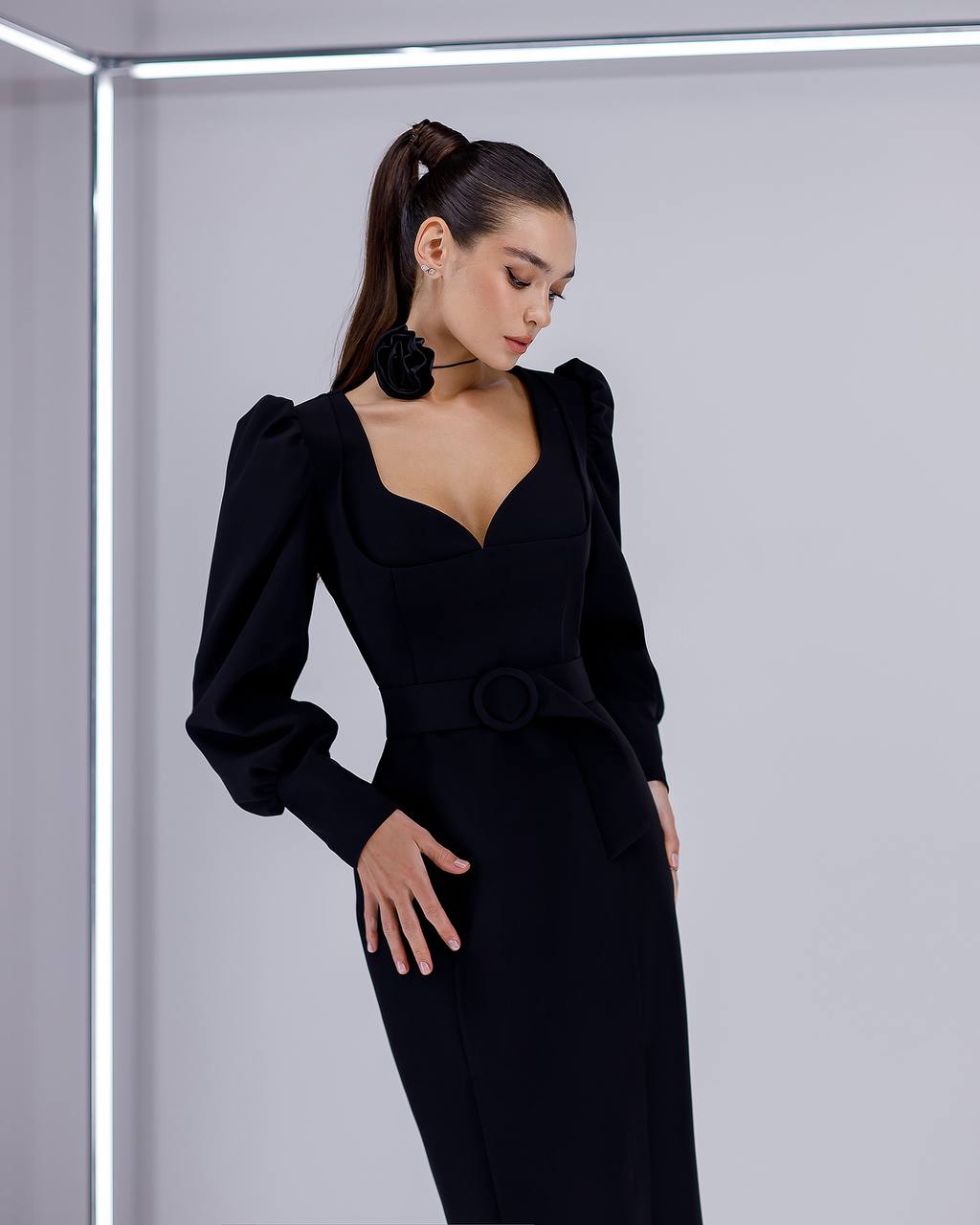 Woman wearing a black dress with puffed sleeves against a light gray background