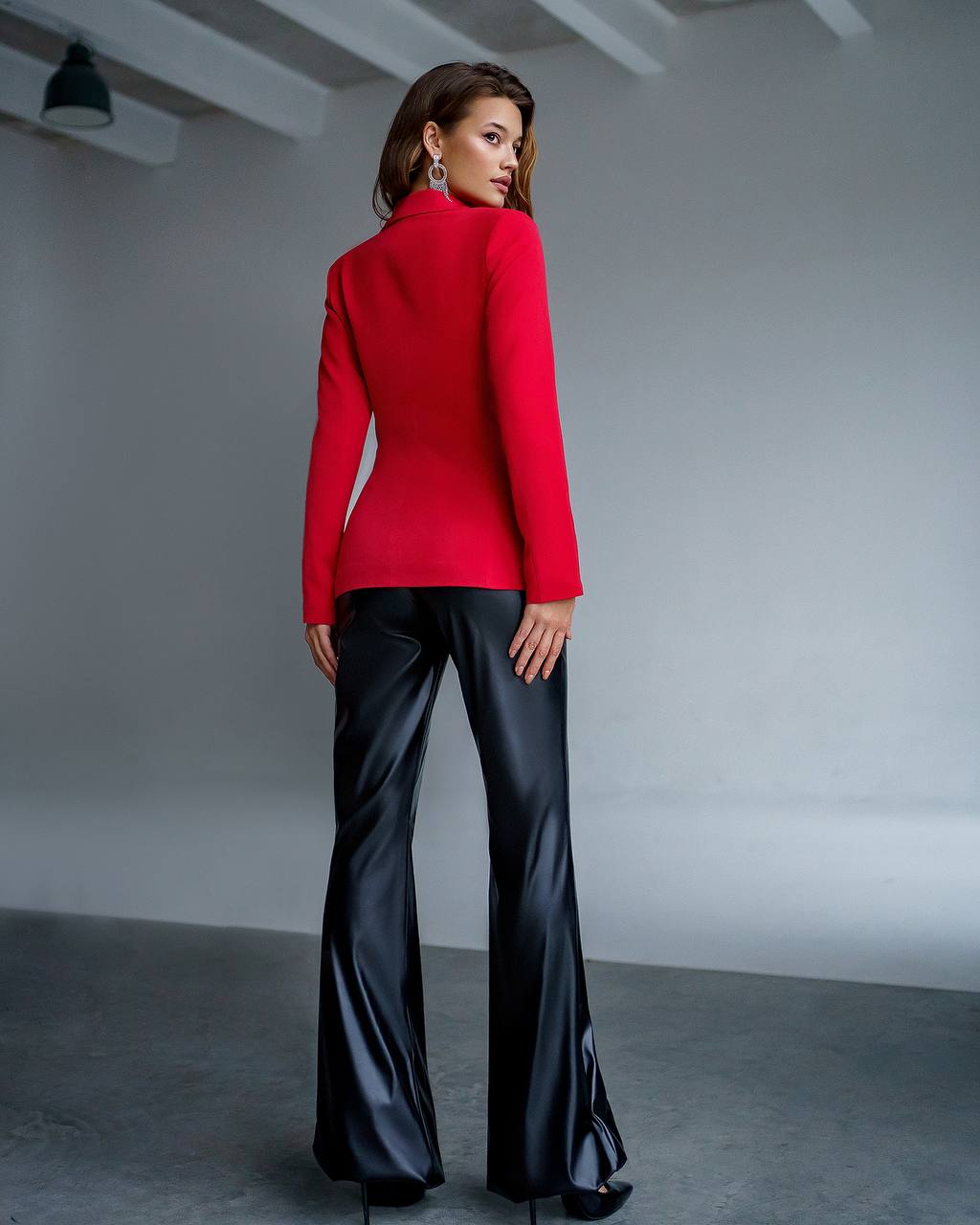Woman wearing a red jacket and black pants in a studio setting