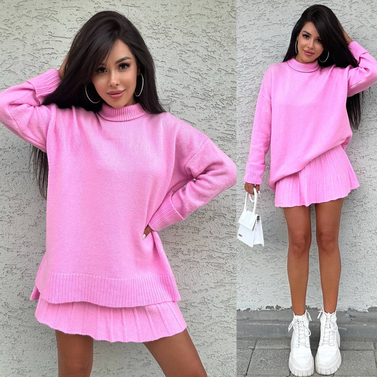 Woman wearing a pink sweater and skirt set against a gray wall.