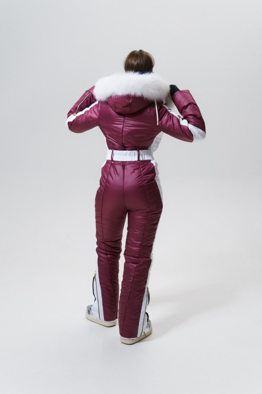 Person wearing a maroon snowsuit with white fur hood on a white background