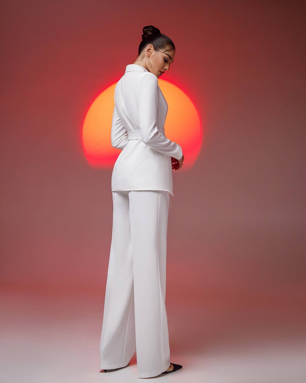 Person wearing a white outfit with a red and orange sun in the background