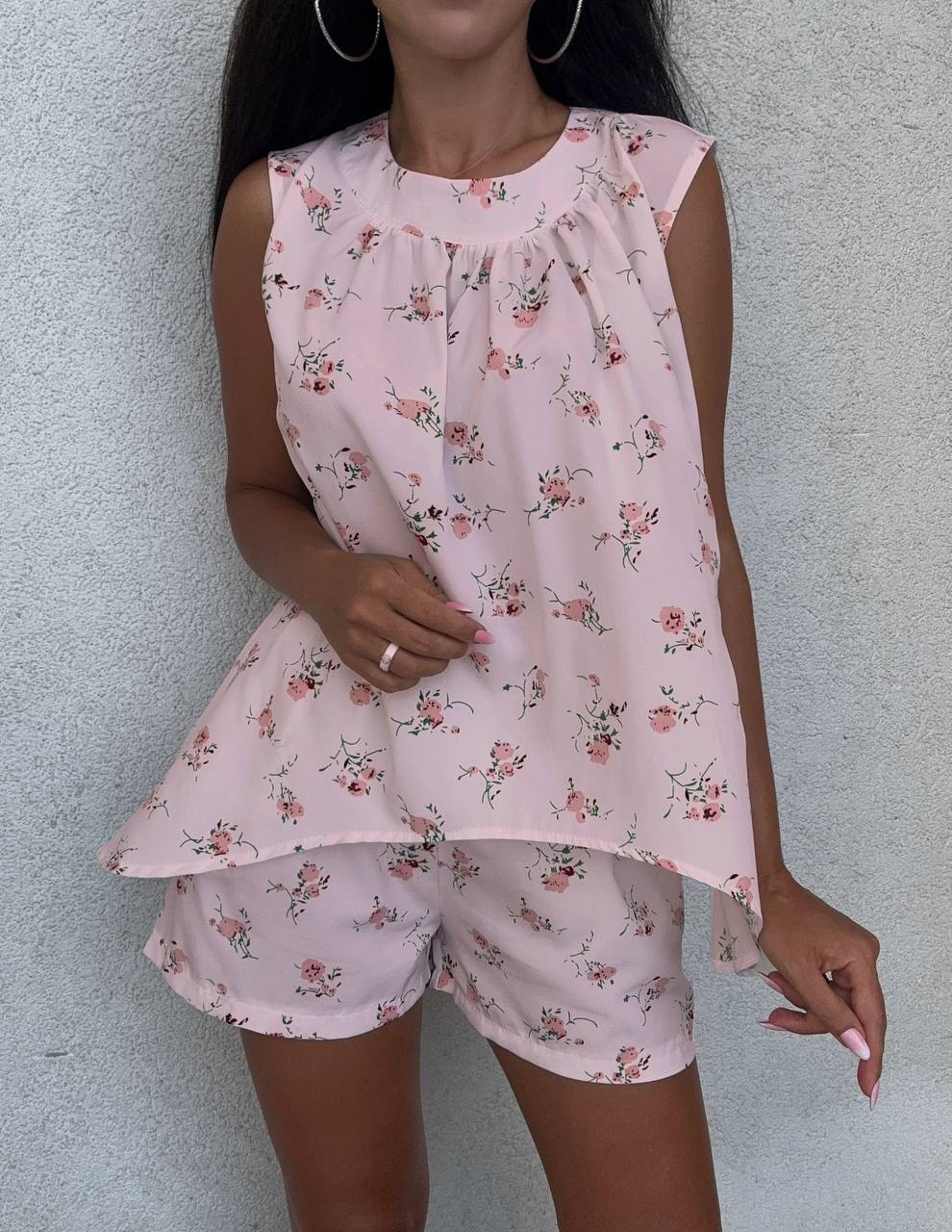 Woman wearing a pink floral pajama set against a light gray background