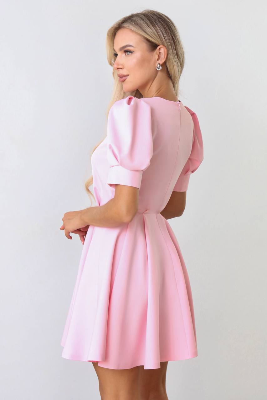 Woman wearing a pink dress with puffed sleeves against a white background
