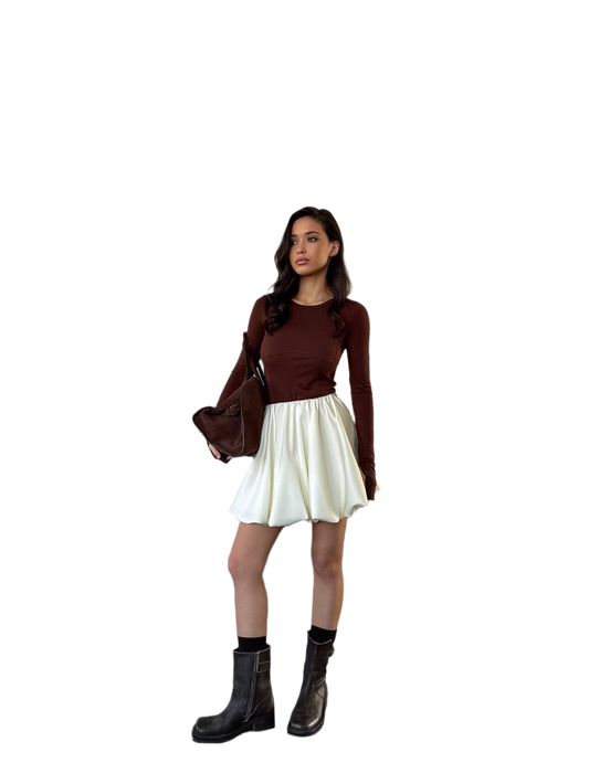 Woman wearing a brown top, white skirt, and black boots on a white background