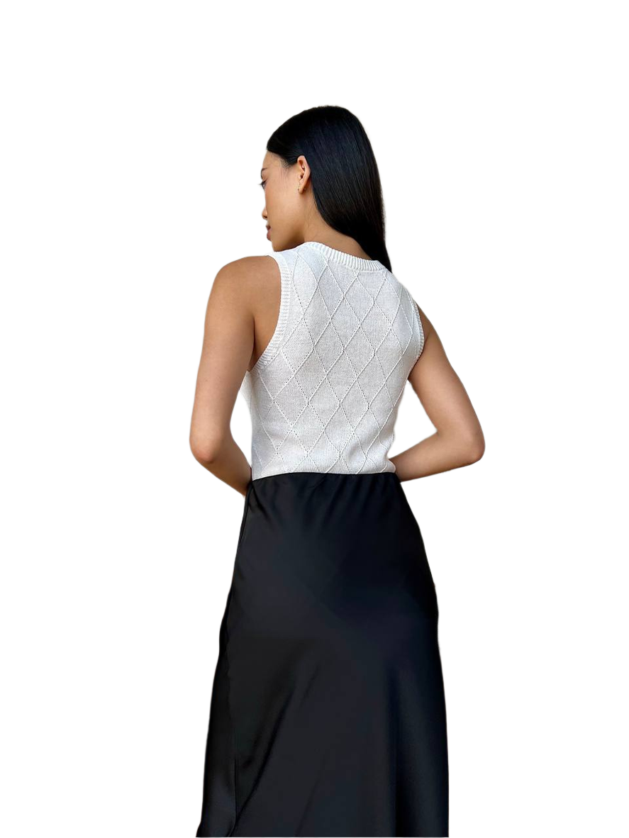 Woman wearing a white top with geometric pattern and black skirt on a white background