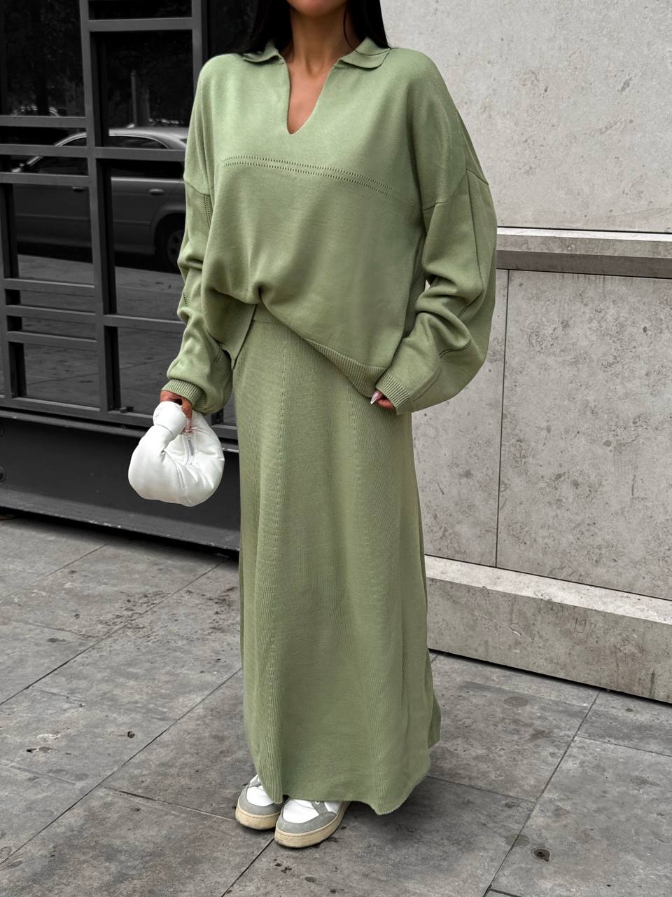 Person wearing a green outfit standing on a city street.