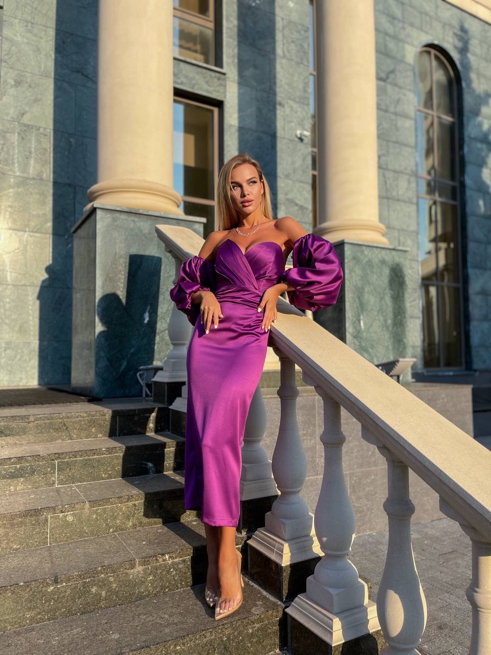 Woman in a purple dress standing on steps in front of classical architecture