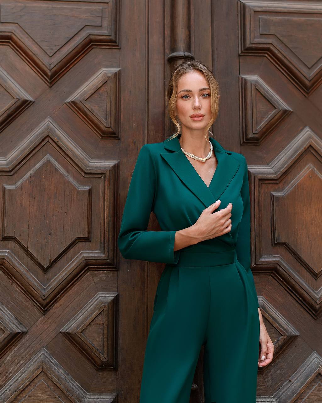 Woman in a teal outfit standing in front of a wooden door