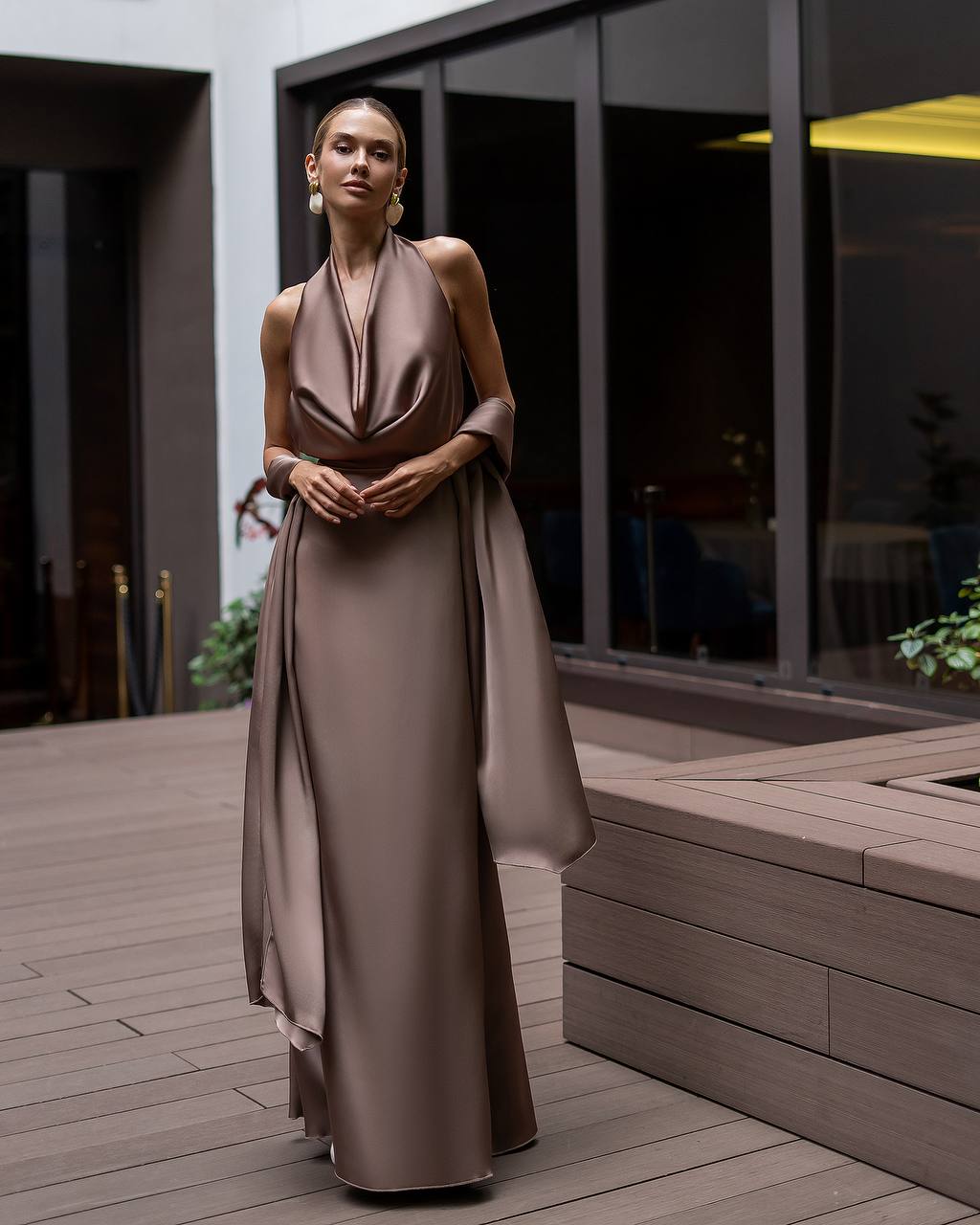 Woman in a long, flowing dress standing on a wooden deck.