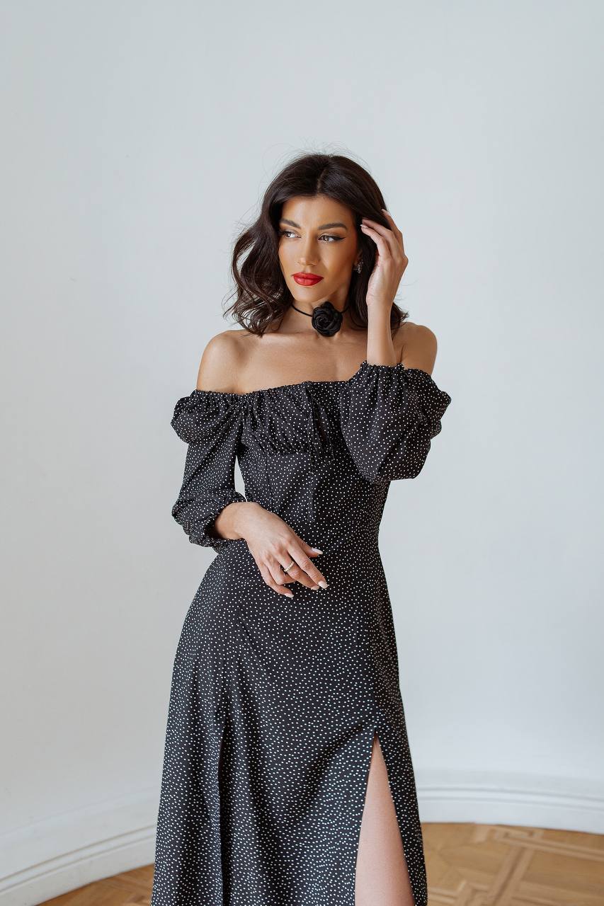 Woman wearing a black polka dot off-shoulder dress with a white background