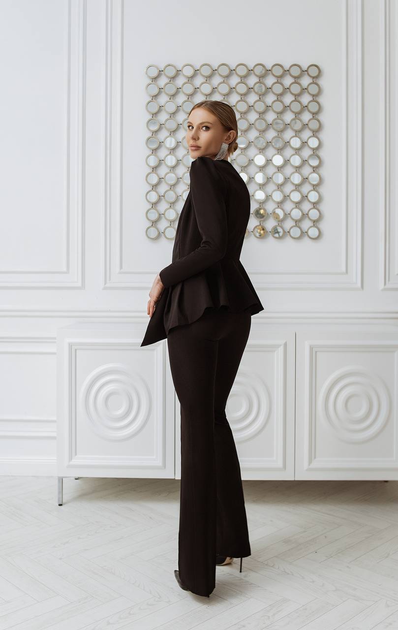 Woman in a black outfit standing in a room with decorative wall panels.
