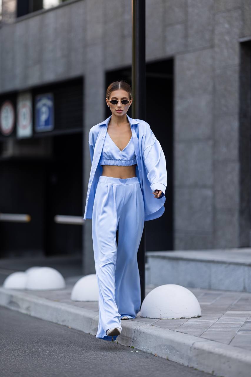 Woman in a blue outfit walking on a city street.