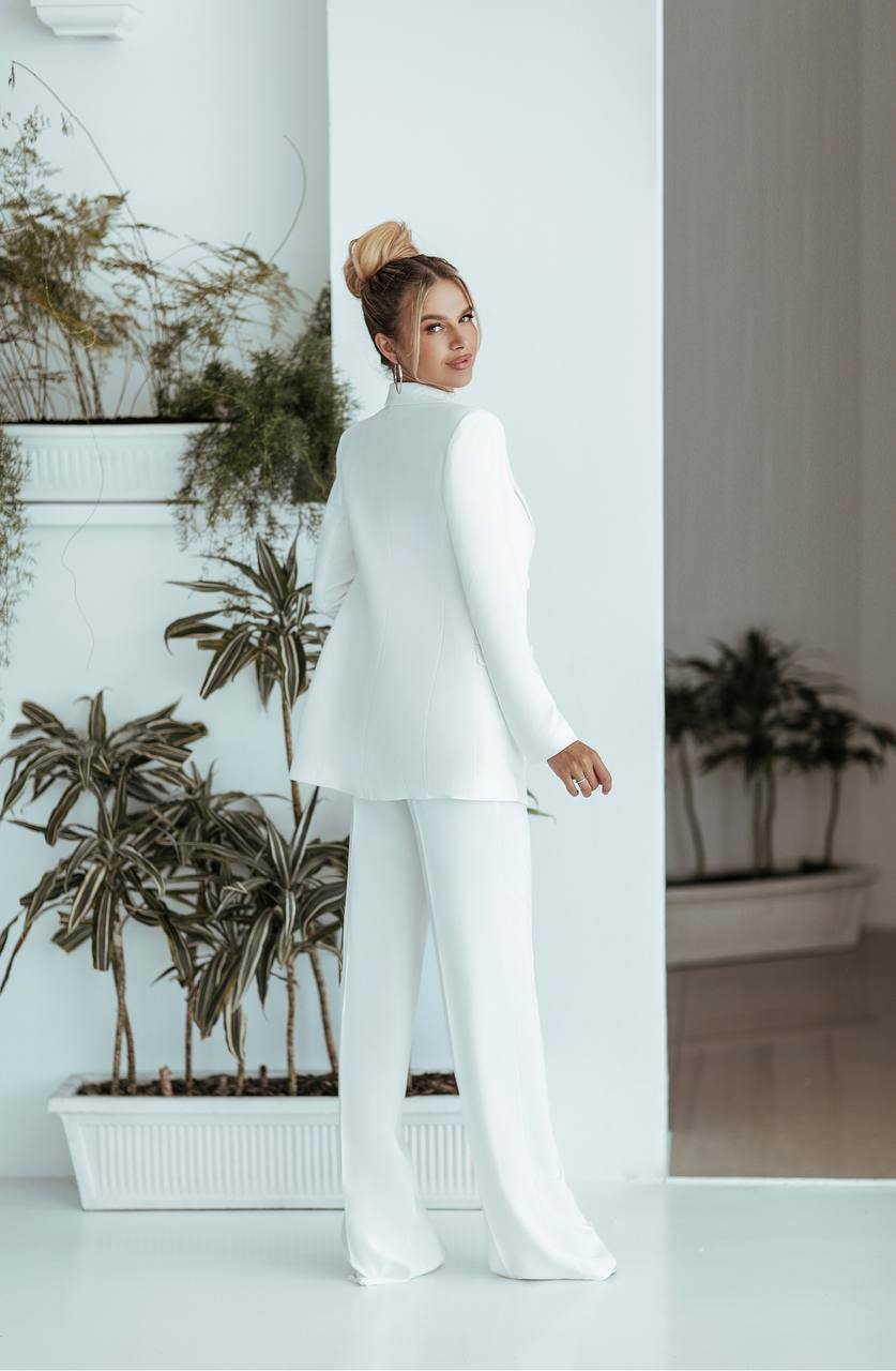 Woman in a white outfit standing in a room with plants