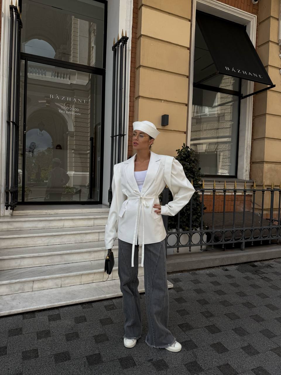 Person wearing a white outfit standing in front of a building with 'Bazrani' on the door.