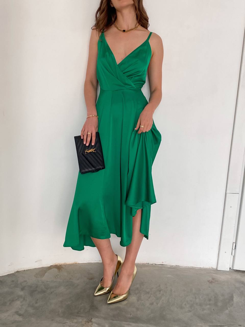 Woman wearing a green dress with gold shoes against a white background