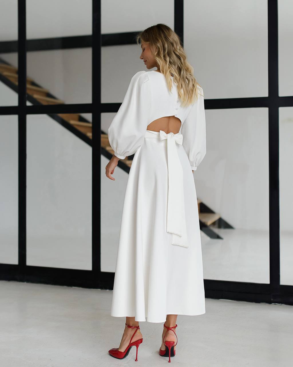 Woman wearing a white dress with cut-out design in a minimalistic setting