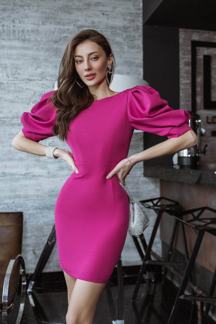Woman in a bright pink dress posing in an indoor setting