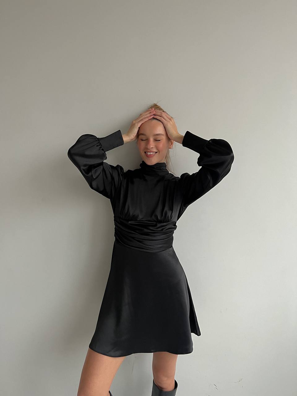 Person wearing a black dress against a plain background