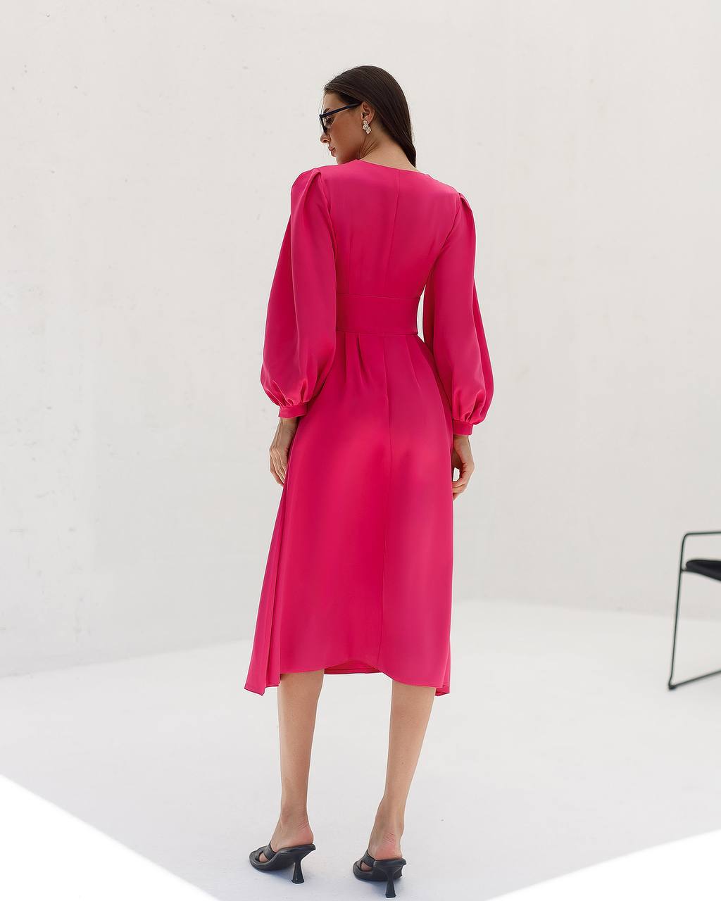 Woman wearing a bright pink dress with long sleeves on a white background