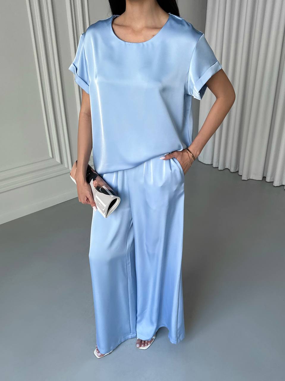 Person wearing a light blue outfit with wide-leg pants against a neutral background