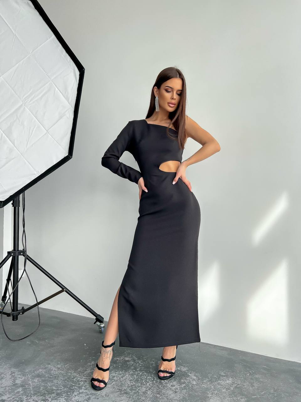 Woman wearing a black dress with cut-out design in a studio setting