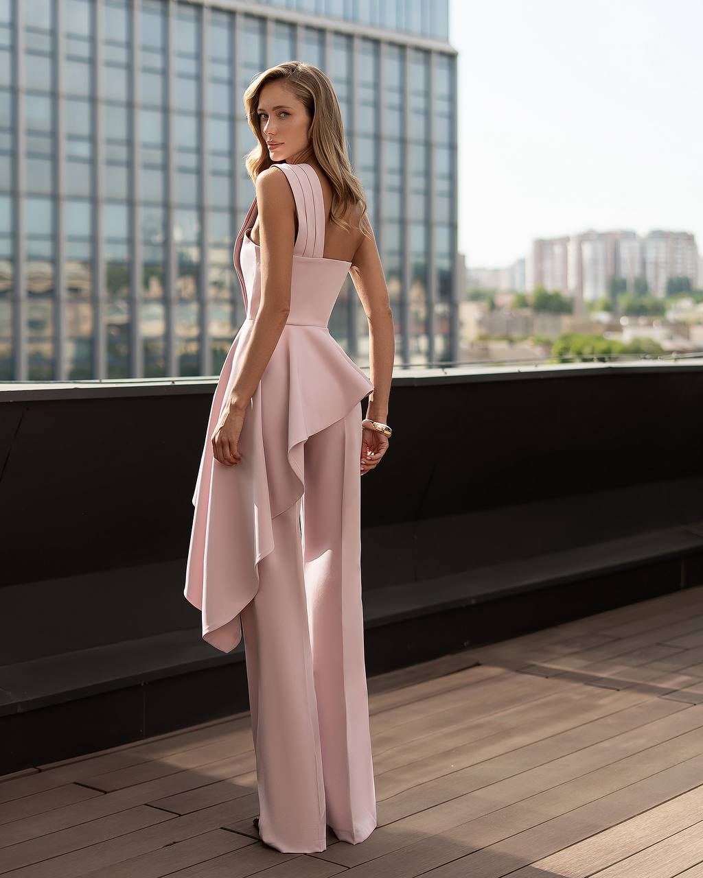 Woman in a pink dress standing on a rooftop with cityscape background